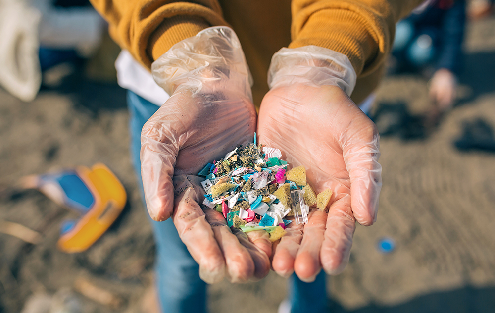 Hands holding tiny plastic fragments illustrate how everyday plastic waste breaks down into microplastics that spread through rivers, oceans and natural ecosystems. Hands holding tiny plastic fragments illustrate how everyday plastic waste breaks down into microplastics that spread through rivers, oceans and natural ecosystems.